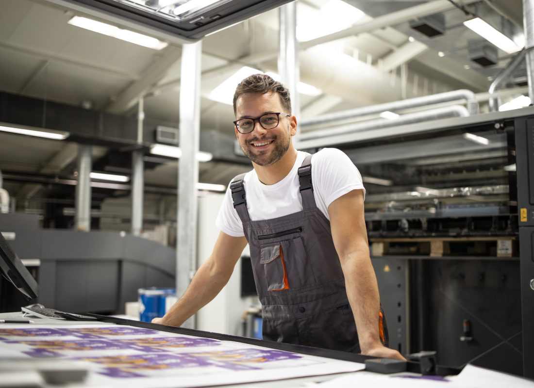 Portrait of worker at control room checking print quality at printing house.